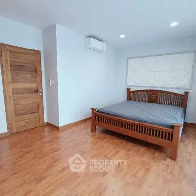 Spacious bedroom with wooden flooring and modern bed frame