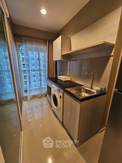 Modern kitchen with washing machine and sleek cabinetry in high-rise apartment