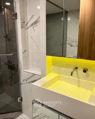 Modern bathroom with sleek design, featuring a glass shower and illuminated vanity.