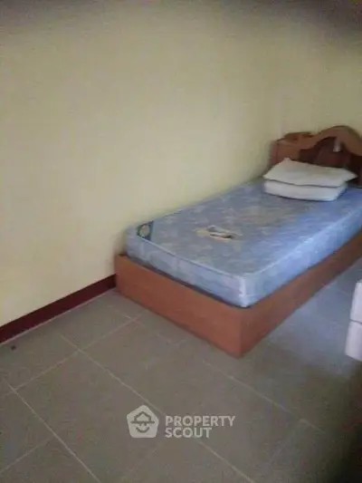 Cozy single bedroom with simple furnishings and tiled flooring, perfect for minimalist living.