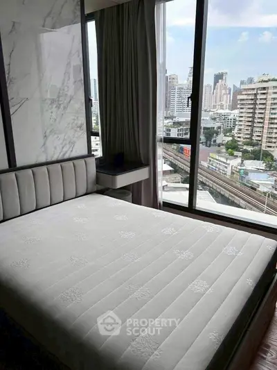 Modern bedroom with city view and large windows in high-rise apartment