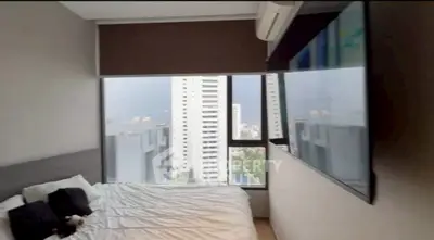 Modern bedroom with city view, large window, and sleek decor in high-rise apartment.