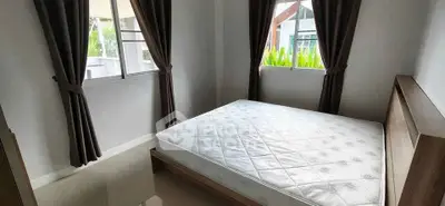 Cozy bedroom with large windows and natural light, featuring a comfortable bed and modern decor.