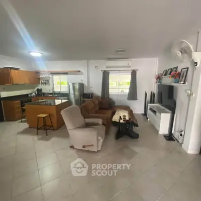 Spacious open-plan living room with modern kitchen and cozy seating area, perfect for entertaining.