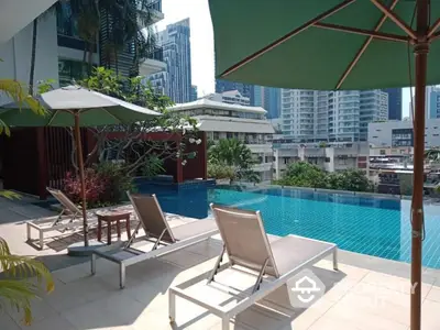 Luxurious rooftop pool with city skyline view and sun loungers in modern apartment complex.