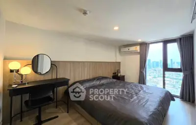 Modern bedroom with city view, featuring a cozy bed, stylish vanity, and large window for natural light.