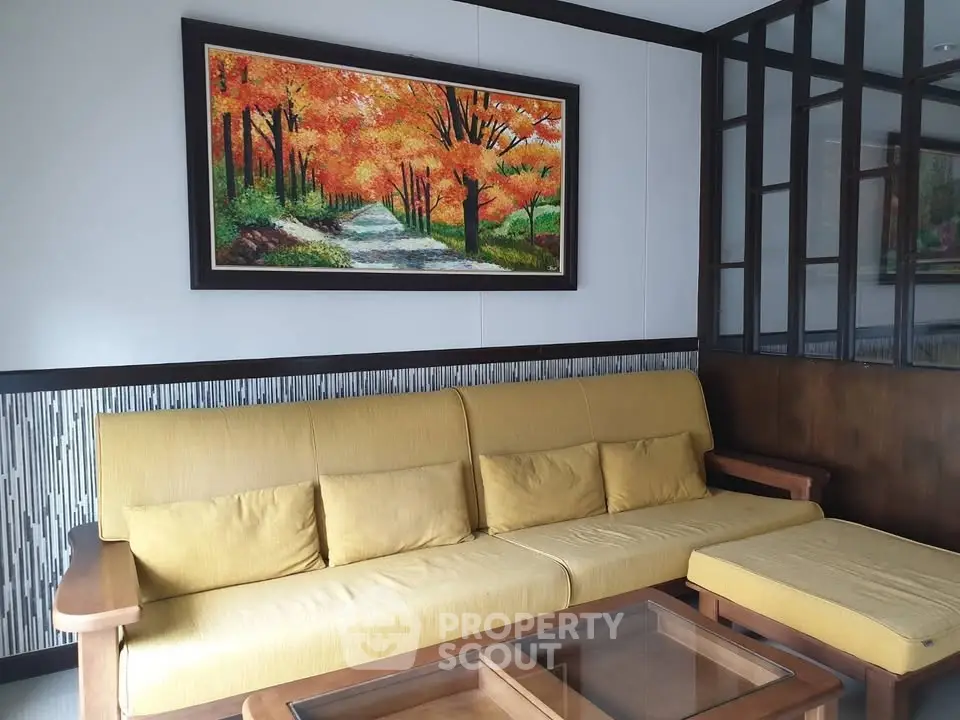 Charming living room with vibrant autumn-themed artwork and cozy yellow sofa set.