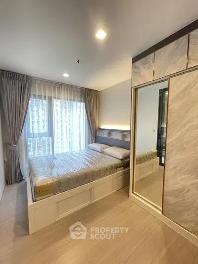 Elegant bedroom with large mirrored wardrobe, plush bedding, and floor-to-ceiling windows draped in luxurious curtains, offering a serene urban retreat.