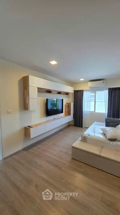 Modern living room with sleek built-in entertainment unit and large window for natural light.