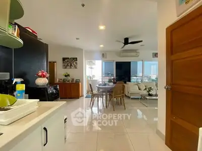 Spacious open-plan living area with modern kitchen and dining space, featuring a large balcony with city views.