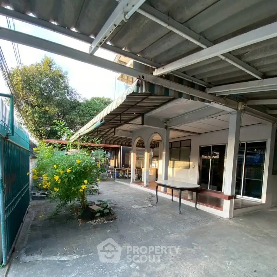 Spacious outdoor area with covered patio and lush greenery, perfect for relaxation and gatherings.