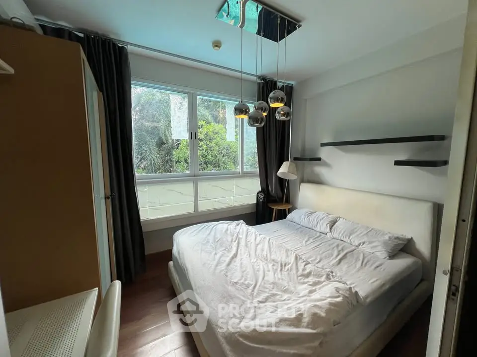 Cozy bedroom with large window and modern lighting in a stylish apartment.