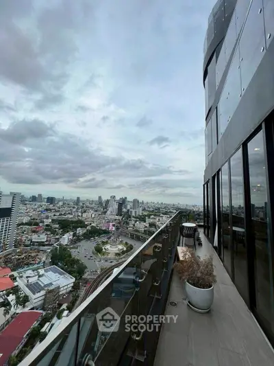 Stunning cityscape view from modern high-rise balcony with glass railing.