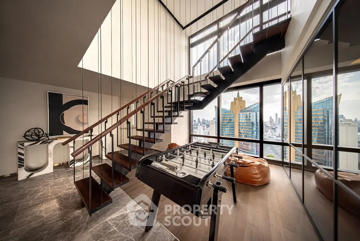 Luxurious penthouse with modern staircase and panoramic city views, featuring a stylish foosball table and chic decor.