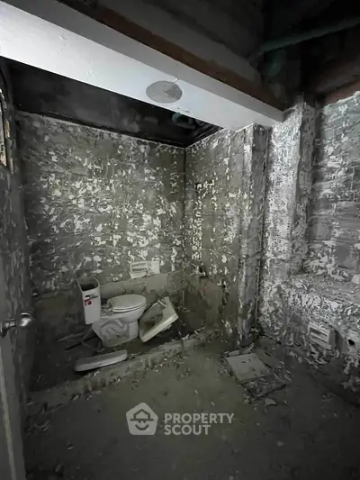 Unfinished bathroom with exposed concrete walls and toilet installation.