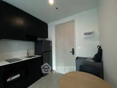 Modern compact kitchen with sleek black cabinets and integrated appliances in a cozy apartment.