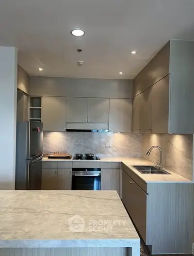 Modern kitchen with sleek cabinetry and built-in appliances, featuring a stylish marble countertop and backsplash.