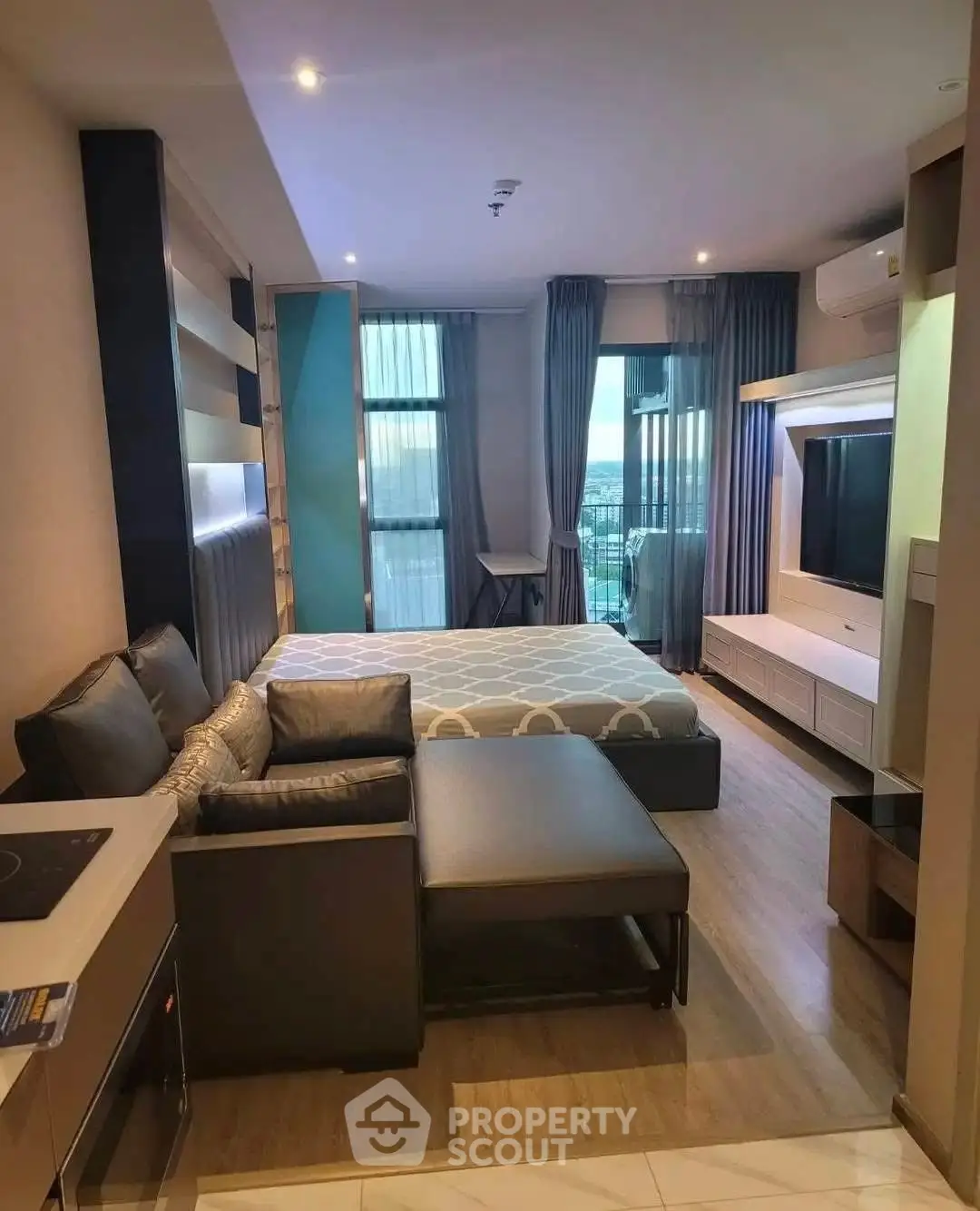 Modern studio apartment with stylish decor and city view, featuring a cozy living area and sleek furniture.