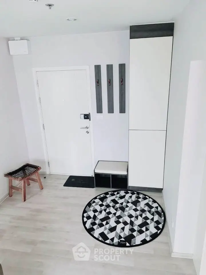 Modern minimalist entryway with geometric rug and sleek storage solutions.