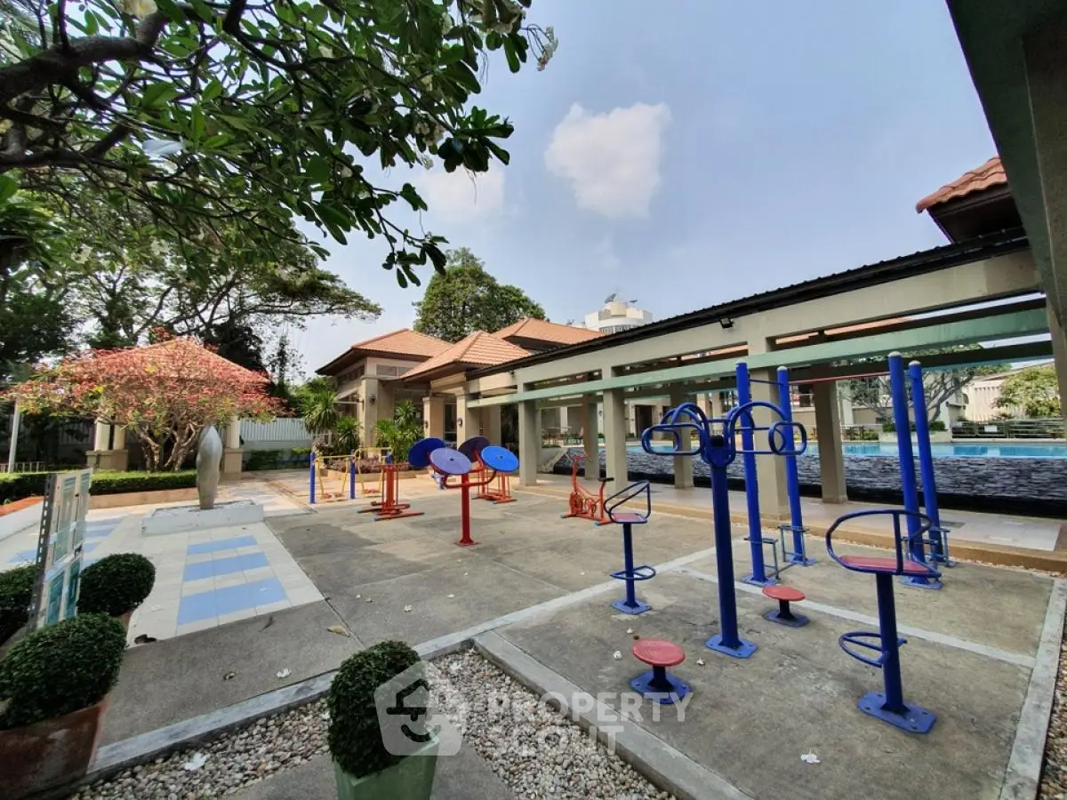 Outdoor gym area with modern equipment and lush greenery in a residential complex