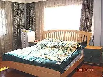 Cozy bedroom with wooden bed frame and elegant curtains, perfect for relaxation.