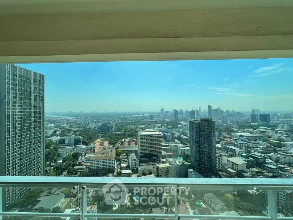 Stunning cityscape view from high-rise balcony showcasing urban skyline and clear blue sky.