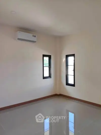 Bright empty room with air conditioning and two windows, perfect for customization.