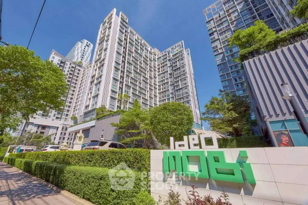 Modern high-rise condominium with lush greenery and clear blue sky, showcasing urban living at its finest.
