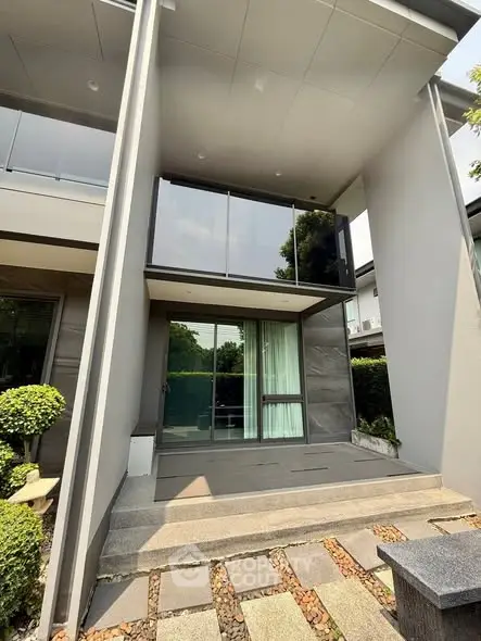 Modern two-story house exterior with sleek design and lush greenery