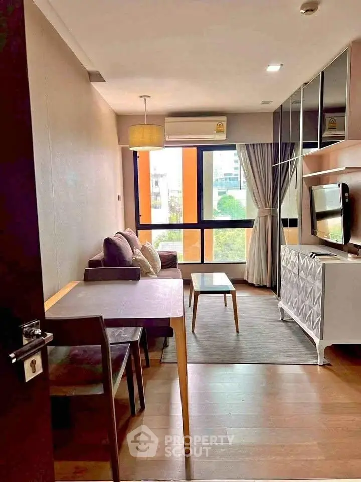 Modern living room with stylish decor and large window offering city views.