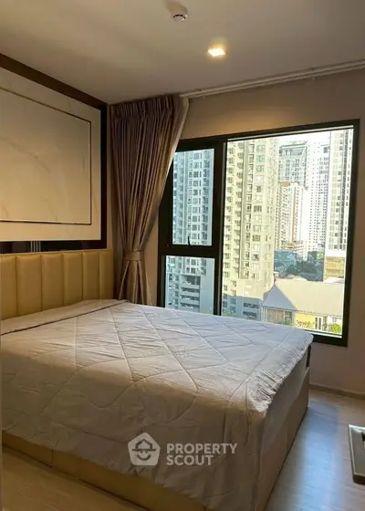 Modern bedroom with large window offering stunning city view in high-rise apartment.