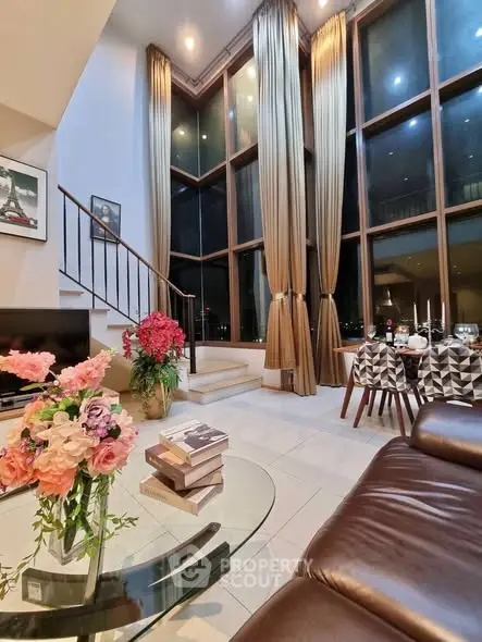 Luxurious high-ceiling living room with elegant decor and large windows offering stunning views.