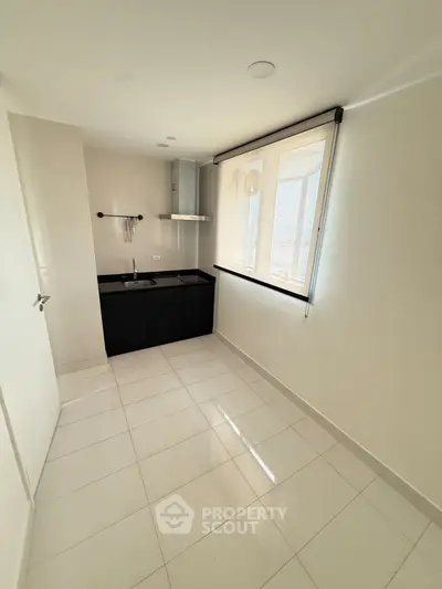 Modern minimalist kitchen with sleek black cabinetry and bright natural lighting.