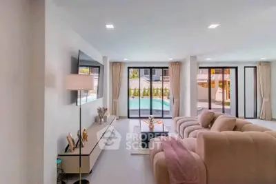 Spacious living room with modern decor and pool view, perfect for relaxation and entertainment.