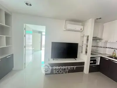 Modern living room with sleek kitchen, TV, and air conditioning in a stylish apartment.