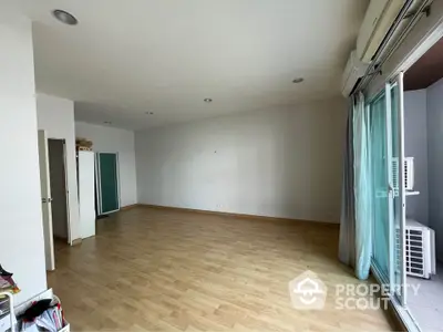 Spacious and well-lit empty living room with hardwood floors, large windows, and an air conditioning unit, ready for customization.