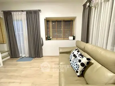Stylish living room with modern decor and cozy seating area, featuring elegant curtains and wooden blinds.