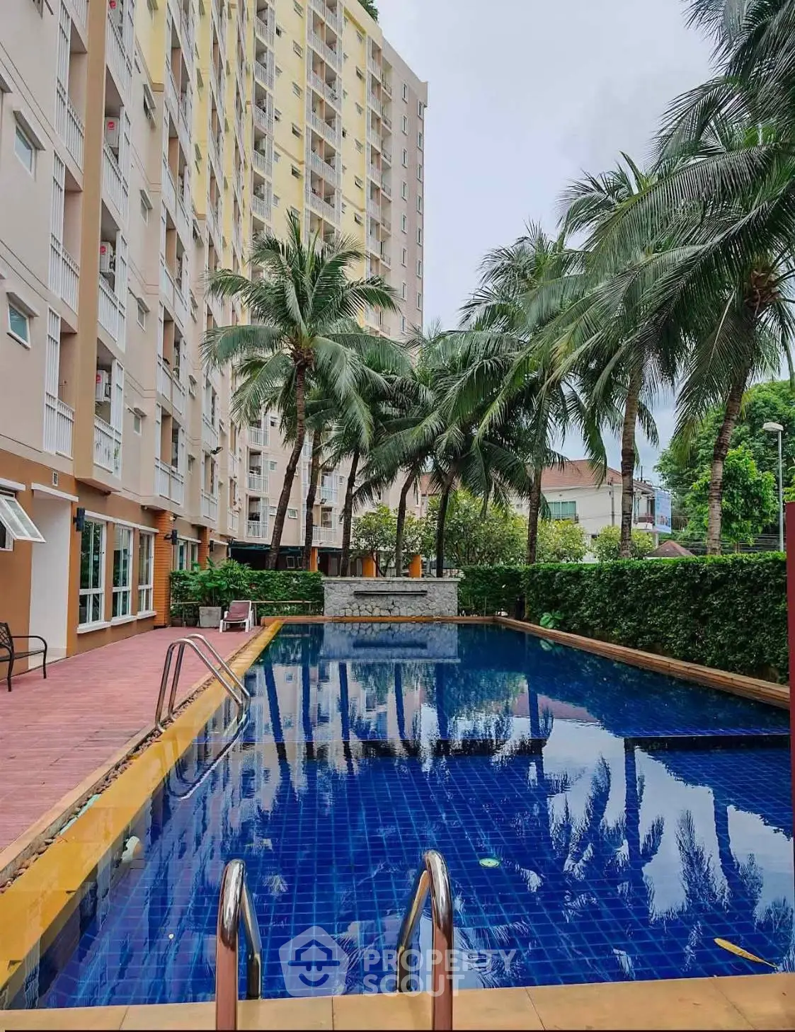 Stunning apartment complex with a luxurious pool surrounded by lush palm trees and modern architecture.