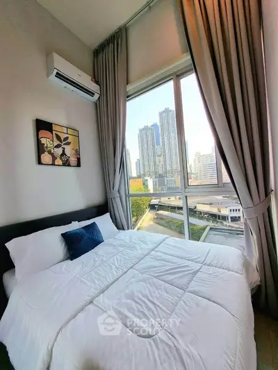 Modern bedroom with large window offering stunning city view in high-rise apartment.