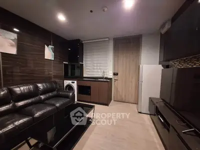 Modern living room with sleek black leather sofa, washing machine, and contemporary kitchen appliances.