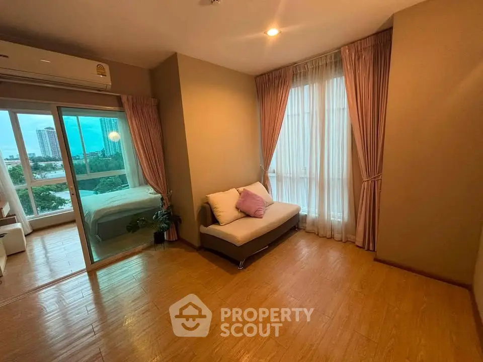 Spacious living room with wooden flooring and large windows offering city views.