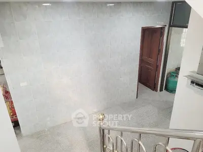 Spacious tiled interior with elegant railing and wooden door