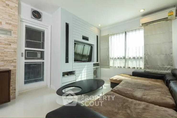 Modern living room with sleek design, large windows, and comfortable seating in a stylish apartment.