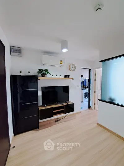 Modern living room with sleek TV unit and air conditioning, featuring light wood flooring.