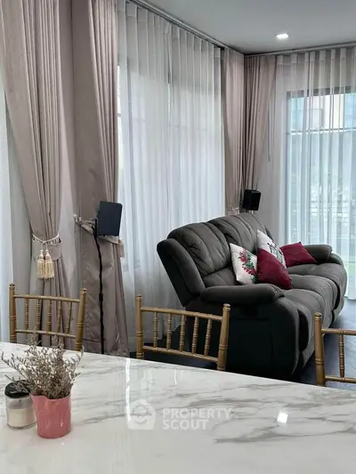 Elegant living room with plush sofa and large windows, perfect for relaxation.