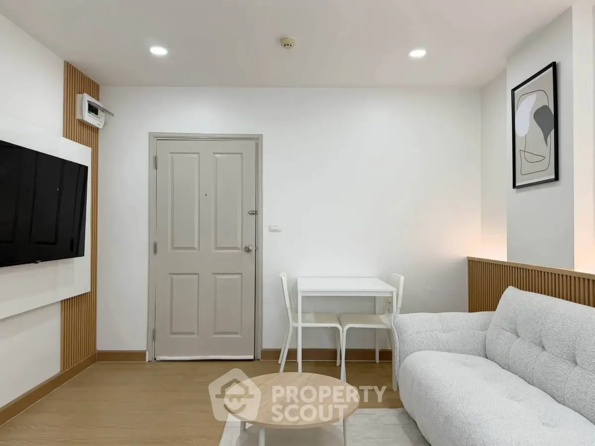 Modern living room with cozy sofa, wall-mounted TV, and minimalist decor
