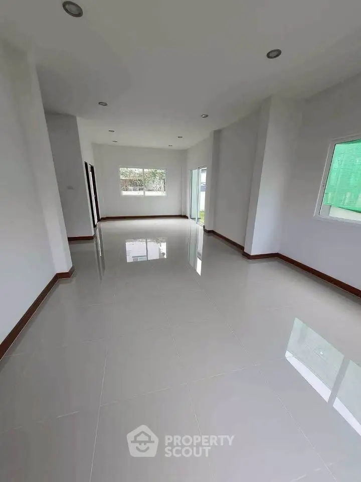Spacious empty room with glossy tiled floors and large windows for natural light.