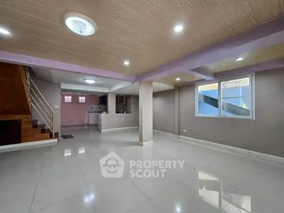 Spacious open-plan living area with modern kitchen and staircase, ideal for family gatherings.