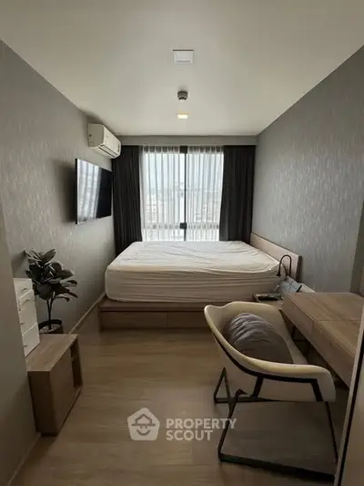 Modern bedroom with sleek furniture and large window offering natural light.