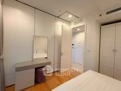 Modern bedroom with sleek white wardrobes and wooden flooring, featuring a stylish vanity area.